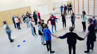 Kuva juhlasalista, jossa lapsia käsi kädessä