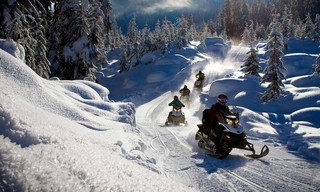 Ihmiset ajavat moottorikelkalla talvisessa maisemassa